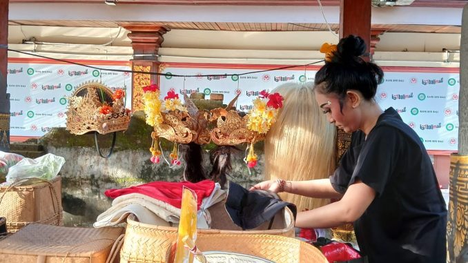 Menyiapkan mahkota. Gita (24) tengah menyiapkan mahkota untuk dikenakan saat tampil menari pada rekasadana (pergelaran) drama tari topeng. Ia bergabung dengan generasi Z lainnya bersama seniornya dari generasi milenial di Sanggar Genta Manik, Kabupaten Gianyar, Bali, sebagai penari. (KanalBali.id/Ayu Sulistyowati)