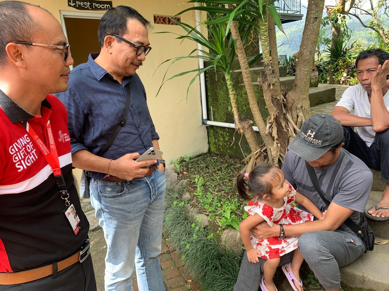 Ketua Kagama bali IGN Agung Diatmika berbincang dengan salah-satu warga yang membawa anaknya melakukan pengecekan mata saat bakti sosial mahasiswa KKN UGM di Munduk, Buleleng, Selasa (8/7/2025) - RFH