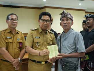 Bupati Adi Arnawa saat menyerahkan buku rekening tabungan kepada 26 Sekaa dan Komunitas Seni yang akan menjadi Duta Kabupaten Badung pada PKB XLVIII Tahun 2026, di Puspem Badung, Senin (13/4). --