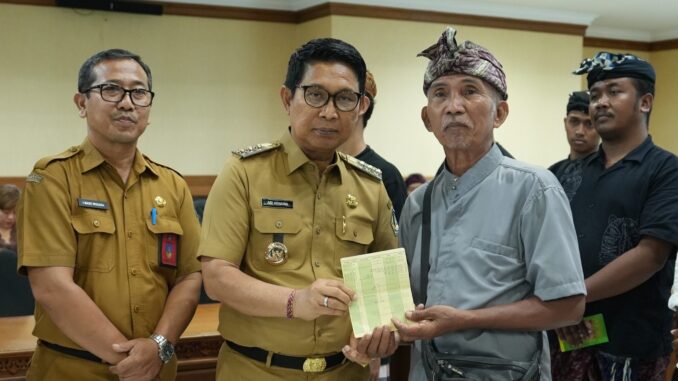 Bupati Adi Arnawa saat menyerahkan buku rekening tabungan kepada 26 Sekaa dan Komunitas Seni yang akan menjadi Duta Kabupaten Badung pada PKB XLVIII Tahun 2026, di Puspem Badung, Senin (13/4). --