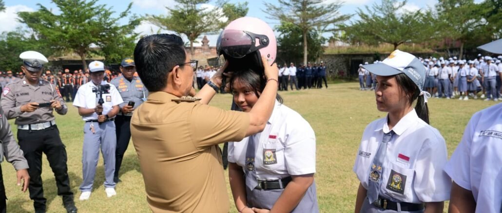 Bupati Adi Arnawa menyerahkan bantuan helm kepada perwakilan siswa-siswi SMA Negeri 2 Abiansemal serangkaian Peringatan Hari Perhubungan Nasional Ke-55 Tahun 2026 tingkat Kabupaten Badung, Senin (14/9).