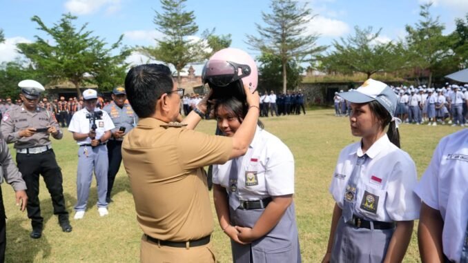 Bupati Adi Arnawa menyerahkan bantuan helm kepada perwakilan siswa-siswi SMA Negeri 2 Abiansemal serangkaian Peringatan Hari Perhubungan Nasional Ke-55 Tahun 2026 tingkat Kabupaten Badung, Senin (14/9).